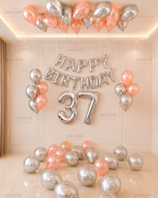 Rose gold and silver birthday balloon setup with number balloons and ceiling balloons in Dubai